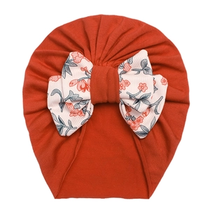 Detail view of baby turban hat in orange with a large floral knot bow decoration