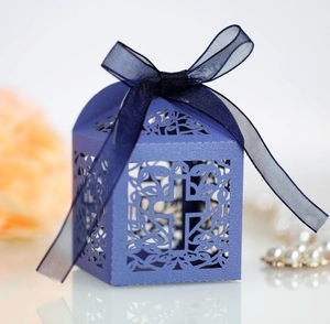 Macro shot of dark blue laser-cut cross wedding gift box with elegant ribbon and floral decor