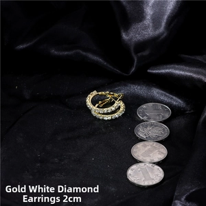 Close-up of 2cm gold-tone hoop earrings with white rhinestones on black silk fabric