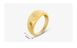 Détail d'une bague dorée de 0,8 cm de large avec zircon serti en étoile et fini poli