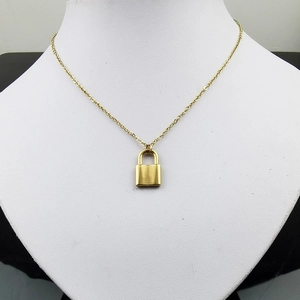 Gros plan d'un pendentif cadenas doré sur une chaîne minimaliste en acier inoxydable