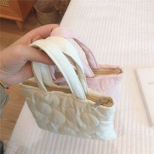 Dettaglio della ricamo floreale trapuntato su mini borse a mano imbottite in nylon