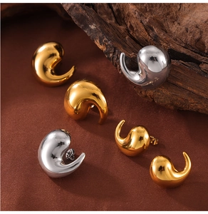 Macro shot of minimalist gold and silver teardrop earrings on a wooden background