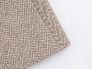 Macro view of brown herringbone wool fabric texture and detailed stitching on the blazer