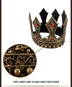 Detail of vintage gold king crown with ornate carvings and inlaid red rhinestones