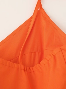 Gros plan détaillé sur la texture du tissu orange et les coutures fines des bretelles