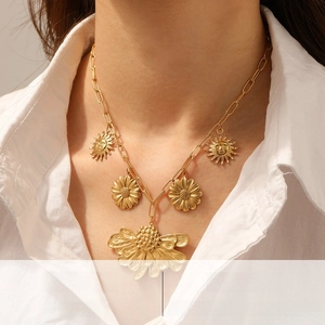 Detail of gold-plated stainless steel paperclip chain with sun and floral charms
