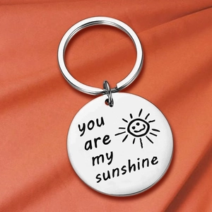 Close-up of silver steel keychain engraved with You Are My Sunshine on orange fabric