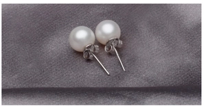 Macro shot of 7-8mm round white pearls with polished silver studs on silk fabric