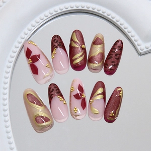 French leopard and floral pattern press-on nails with gold 3D accents on a mirror