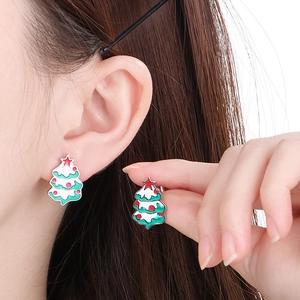 Gros plan de boucles d'oreilles sapin de Noël avec émail coloré sur un modèle féminin