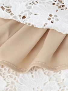 Gros plan détaillé de la dentelle florale blanche sur un tissu lisse champagne