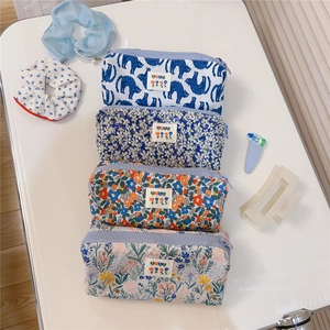 Detail of four floral canvas pouches with zippers in blue, purple, orange, and green colors