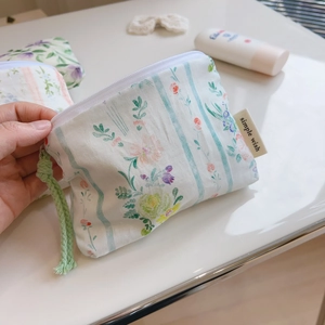 Detail of floral canvas pouch with simple wish label and green woven handle strap