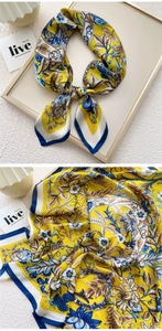 Detailed close-up of a vintage floral silk scarf with baroque patterns and yellow satin texture