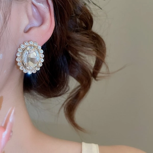 Detail of silver oval stud earrings featuring a crystal center with a diamond halo