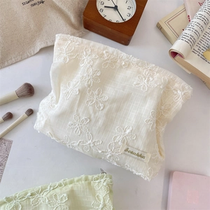 Detail of delicate 3D floral embroidery and checkered texture on a lace cosmetic bag
