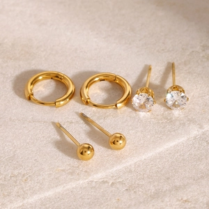 Three pairs of stainless steel earrings featuring gold hoops, zircon studs, and bead studs