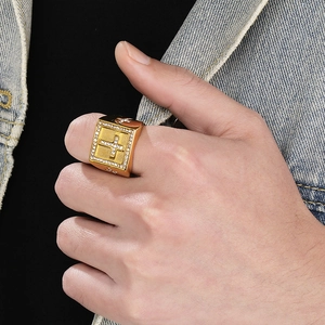 Close-up of golden square signet ring with inlaid crystals and cross pattern for men
