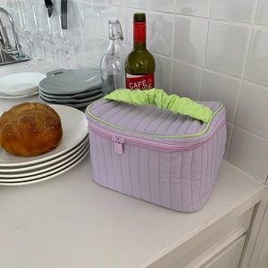 Close-up of lavender quilted makeup bag with contrast light green ruffled handle and trim