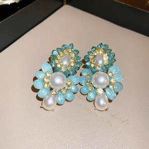 Close-up of vintage flower earrings with blue crystals, pearls and gold finish