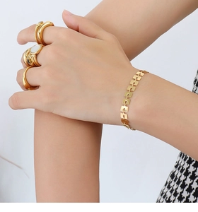 Dettaglio di bracciale in acciaio inossidabile placcato oro 18k e anelli sulla mano