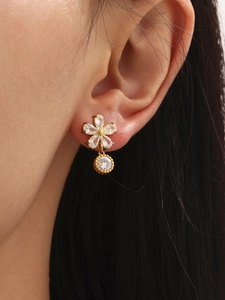 Vue rapprochée d'élégantes boucles d'oreilles fleur en zircon doré portées par un mannequin