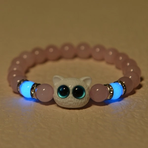Detailed shot of glowing blue beads and pink tiger eye stone bracelet with owl charm