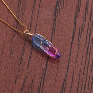 Colorful crystal pillar pendant necklace with gold wire wrapping on dark wood background