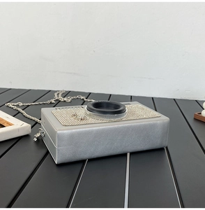 Detailopname van de cameravormige tas met Spotlight-gravure en een metalen kettingriem
