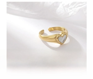 Detailed close-up of a gold titanium steel ring featuring a white heart shell inlay