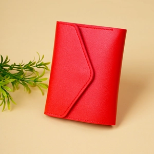 Detail of red faux leather wallet with lychee texture and stitching on cream background
