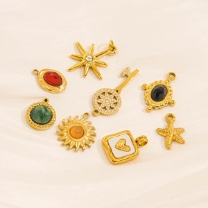 Golden sun and heart pendant charms with colorful gemstones on white fabric
