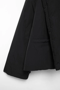 Detailansicht der schwarzen Minimal-Jacke mit Seitentasche und Manschettenknopf-Akzenten