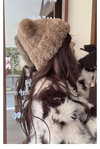 Detail view of a thick brown faux fur bear ear hat with protective earflaps for winter