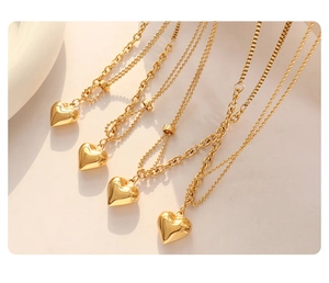 Detail of four golden heart pendant necklaces featuring bead and cable chain styles