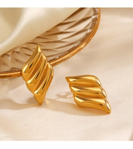 Detailed macro view of triple-layered golden earrings with polished mirror finish