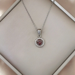 Detail showing a round ruby pendant with halo setting in a luxury jewelry box