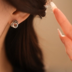 Gros plan d'une boucle d'oreille nœud torsadé en argent portée par un mannequin élégant