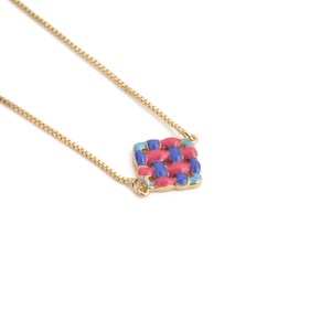 Gold chain bracelet with square woven pendant in pink and blue enamel on white back