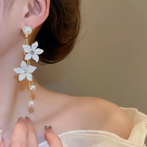 Detail shot of elegant floral pearl tassel earrings with rhinestones on a female model