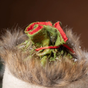 Christmas gift bag with green fabric and red drawstring in a soft faux fur base