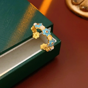 Macro detail of 18k gold plated open ring with blue enamel flowers and cat eye beads