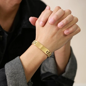 Close-up of golden stainless steel bracelet with curved nameplate on male wrist