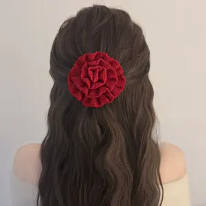 Detail of red 3D rose hair scrunchie with lace texture on long brown wavy hair