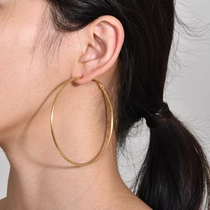 Classic large golden stainless steel hoop earrings worn by a model in a minimalist style