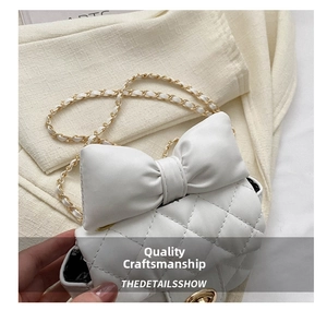Detail of white quilted crossbody bag with oversized bow and golden metal twist lock