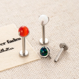 F136 Titan Labret Piercing mit buntem Opal-Aufsatz auf beigem Stoffhintergrund