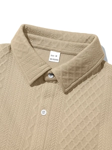 Macro detail of beige knit shirt collar featuring diamond texture and 100% polyester label