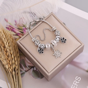 Silver beaded bracelet with black enamel flowers and crystal snowflake charms on jewelry box
